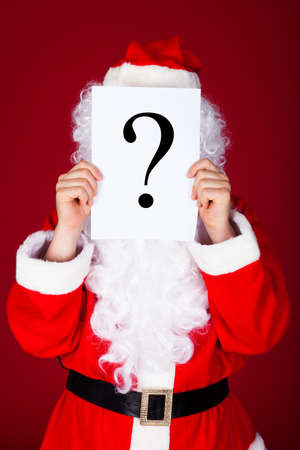 Portrait of a santa holding question mark in front of his faceの写真素材