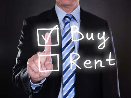 Businessman selecting buy option on the screen over black backgroundの写真素材