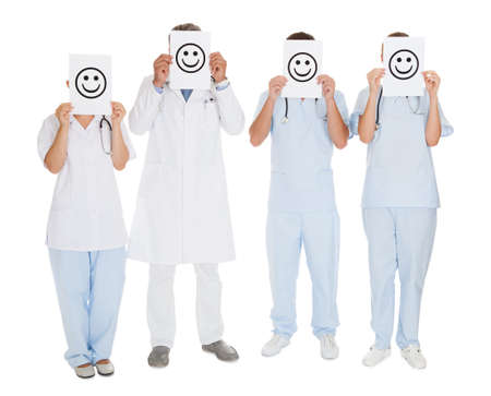 Team Of A Doctors Holding Smiley Icon Sign In Front Of Face Over White Backgroundの写真素材