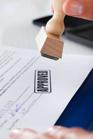 Close-up Of Business Man Hand Pressing Rubber Stamp On Documentの写真素材