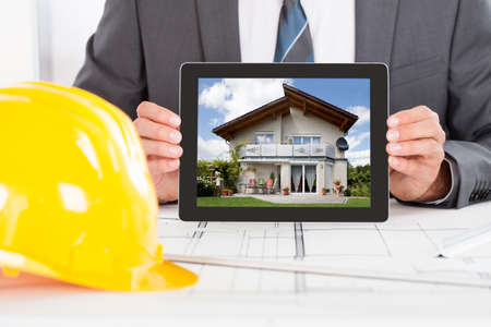 Close-up Of Male Architect Holding Digital Tablet In Front Of Hardhatの写真素材