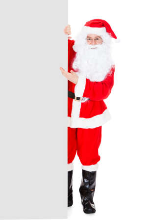 Portrait of a santa holding blank placard over white backgroundの写真素材