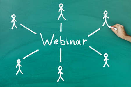 Hand holding chalk drawing webinar concept on green blackboardの写真素材