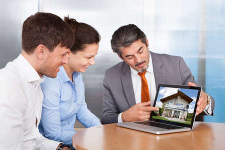Happy Young Couple Discussing With Mature Consultant