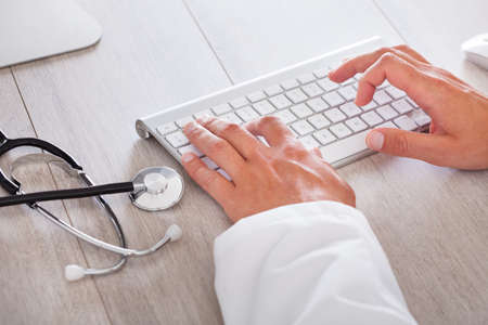 Close-up Of Male Doctor's Hand Typing On Computer Keyboardの写真素材