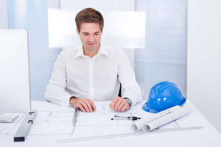 Portrait Of A Young Architect Drawing Plan On Blueprint