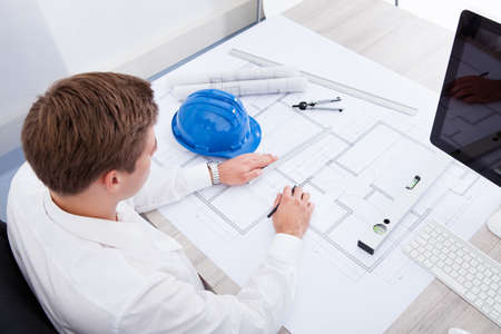 Portrait Of A Young Architect Drawing Plan On Blueprintの写真素材