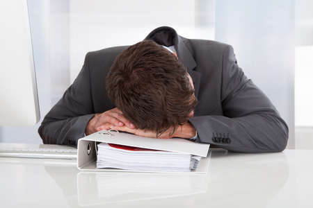 Tired Businessman Sleeping Over Folder At Office