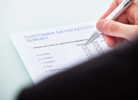 Close-up Of Man's Hand Filling Customer Survey Formの写真素材