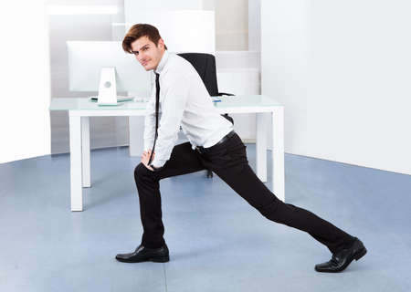 Portrait Of A Young Businessman Stretching In Officeの写真素材