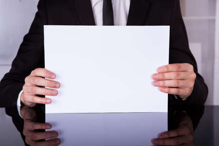 Close-up Of A Businessman Showing Blank Placard At Deskの写真素材