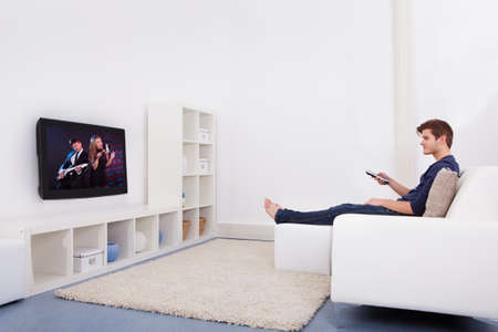 Young Man Sitting On Couch Watching Television
