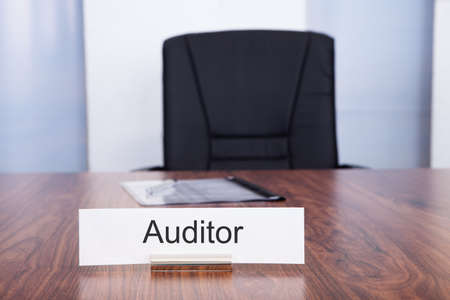 Nameplate With Auditor Title Kept On Desk In Front Of Empty Chairの写真素材