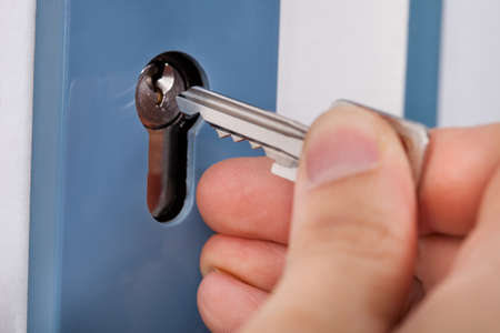 Close-up Of Hand Putting House Key Into Door