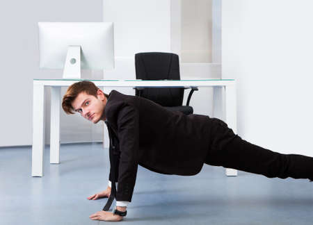Young Businessman Doing Pushups At His Workplaceの写真素材