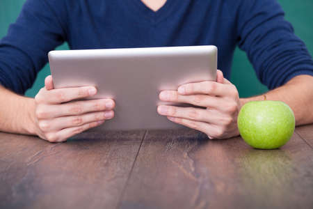 Man Using Holding Digital Tablet In Front Of Green Chalkboardの写真素材