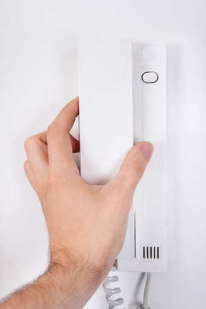 Hand Holding Receiver Attached On White Wall