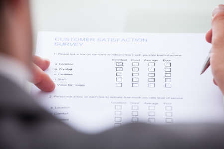 Close-up Of Businessman Filling Customer Survey Form