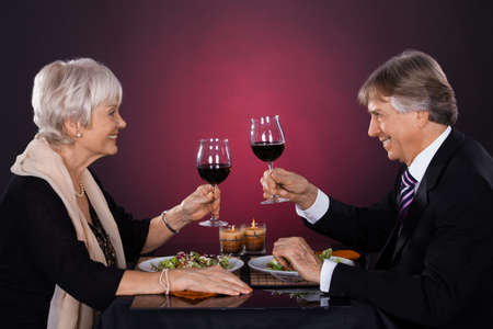 Happy Senior Couple Dining Together With Wine In A Restaurantの写真素材