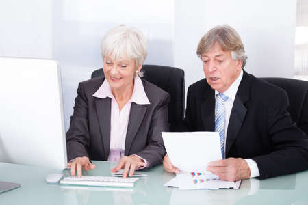Mature Businessman And Businesswoman Looking At Computerの写真素材