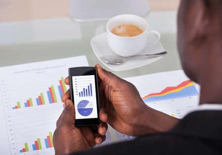 Close-up Of A Businessman Analyzing Graph On Cellphoneの写真素材