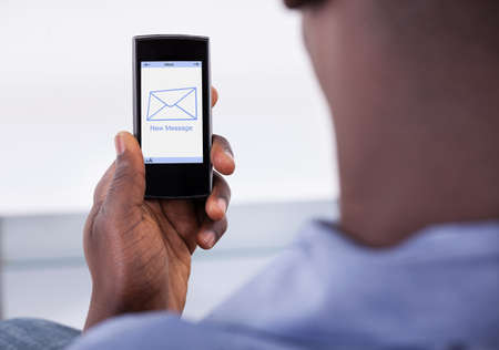 Close-up Of Person Holding Mobile Phone With One New Message Showing On A Screen
