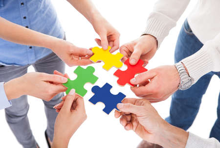 Close-up Of Five People Hand Holding Colorful Puzzle Over White Background