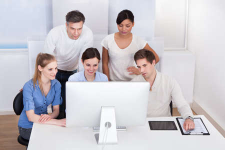 Group Of Happy Businesspeople Working On Computer At Office
