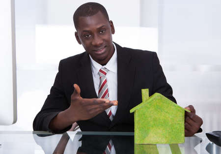 African Young Businessman Sitting At Office Presenting Ecological Houseの写真素材