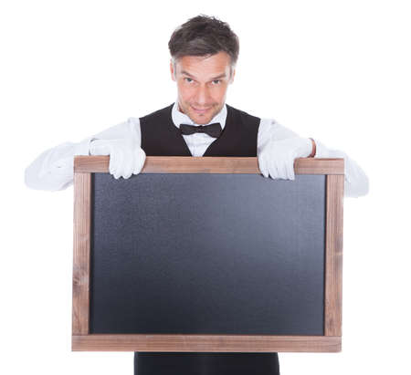 Portrait Of A Happy Smiling Waiter Holding Blank Chalkboardの写真素材