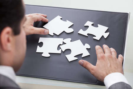 Close-up Of A Businessman Solving Jigsaw Puzzle