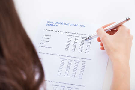 Close-up Of Woman's Hand Holding Pen Over Survey Formの写真素材
