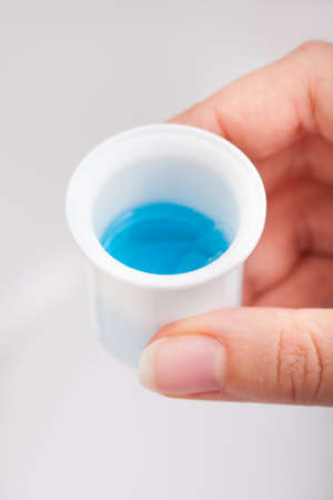 Close-up Of Person's Hand Pouring Liquid In Container