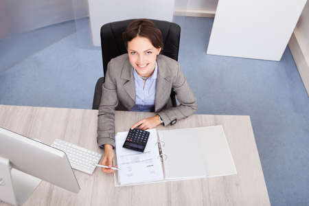 Portrait Of Smiling Young Female Accountant Calculating Bills
