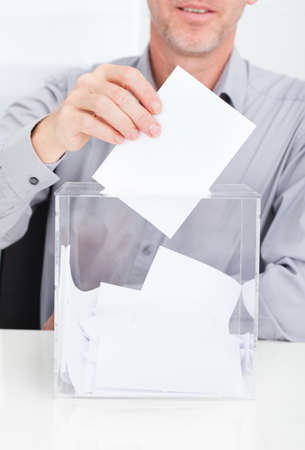 Close-up Of Person Inserting Ballot In Transparent Boxの写真素材