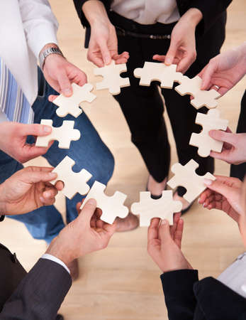 High Angle View Of Business People Assembling Jigsaw Puzzle
