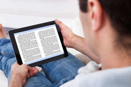 Close-up Of Man Holding Touch Screen Device Showing An E-book