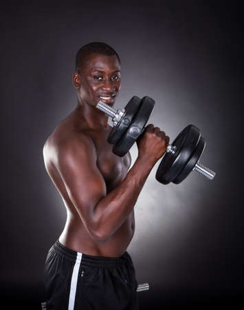 Portrait Of A Young African Man Exercising With Dumbbells