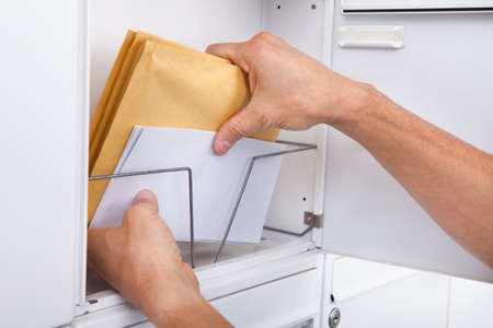Close-up Of Postman's Hand Keeping Letters In Mailbox