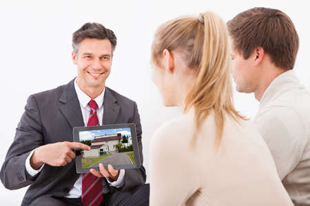 Happy Estate Agent Showing House On Tablet Pc To Couple At Homeの写真素材