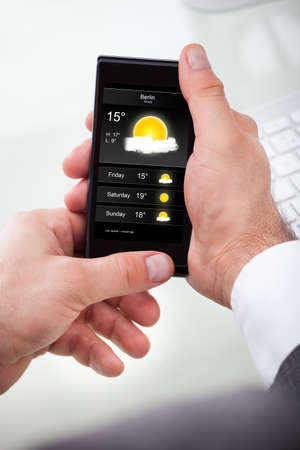 Close-up Of A Businessman Looking Weather Forecast On Cellphone