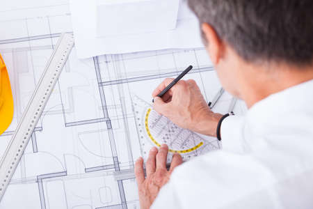 Close-up Of Male Architect Drawing Blueprint In Office