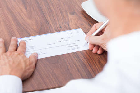 Male Hand Filling Out The Amount On A Cheque
