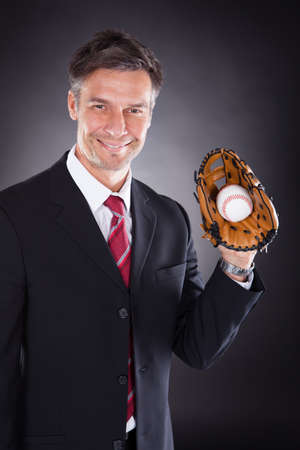 Happy Mature Businessman Holding Baseball And Mitt Over Black Background