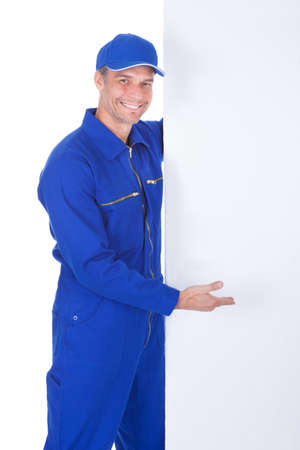 Portrait Of Male Worker In Boilersuit Presenting Blank Placardの写真素材