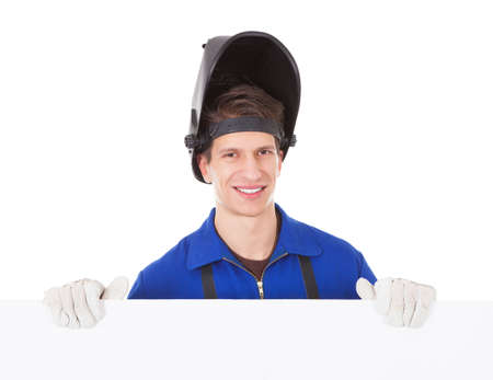 Portrait Of A Young Male Welder Holding Placard Over White Background