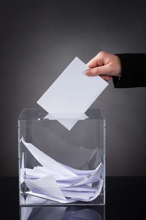 Close-up Of Hand Putting Ballot In Glass Boxの写真素材