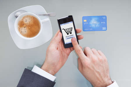 Close-up Of Businessperson Hand Holding Mobile Phone With Online Shopping Application