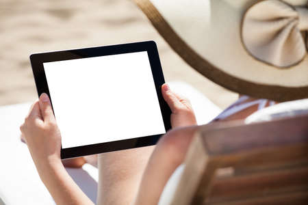 Woman using digital tablet with blank screen while relaxing on beach chair