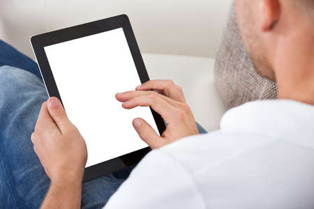 Man using his fingers to navigate on a tablet-pc  over the shoulder view of the blank touchscreen